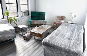 A lounge room with all the furniture prepped to move in plastic wrap.