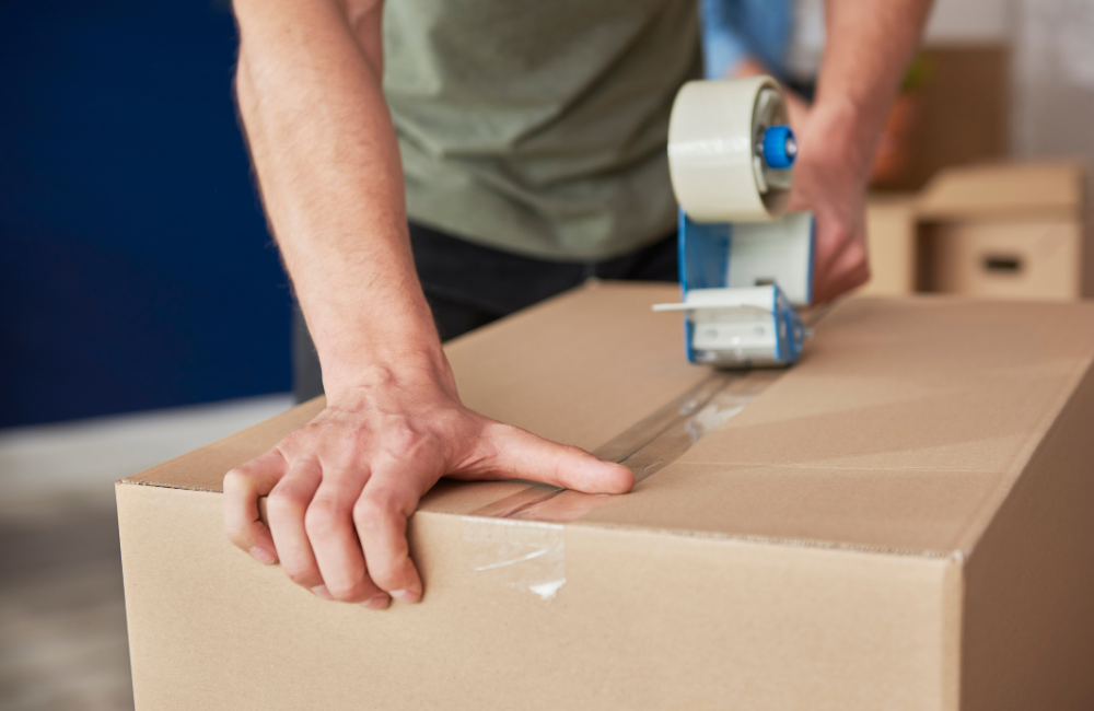 A man taping up a moving box.