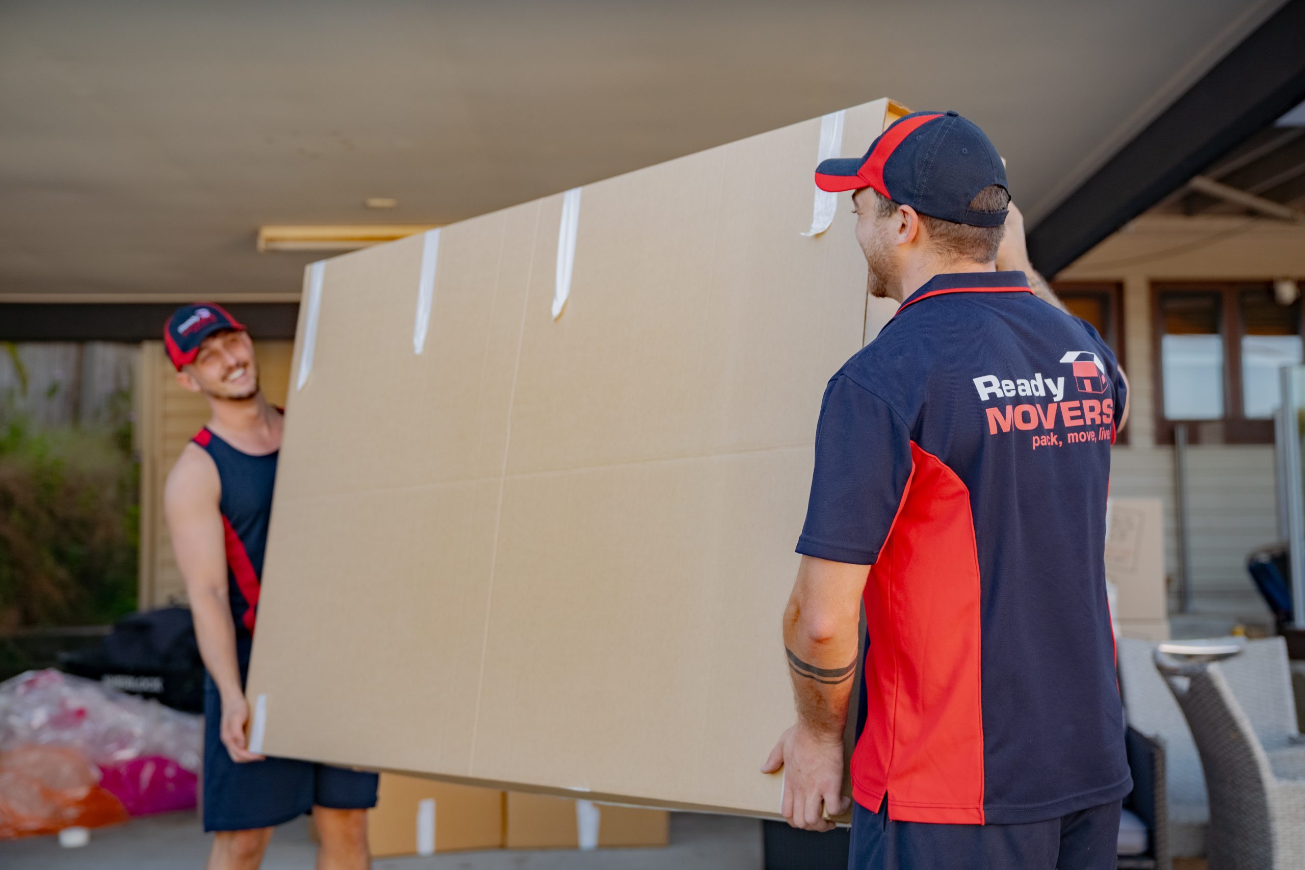 Two Ready Movers removalists lifting a TV box. 