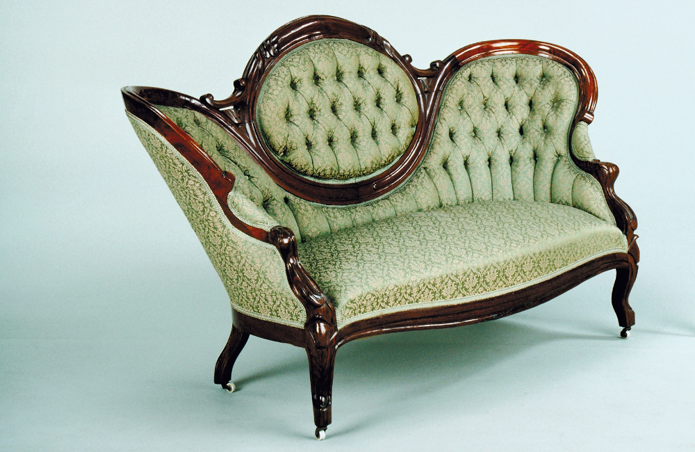 An antique sofa with dark wood trimming and lime green fabric. 