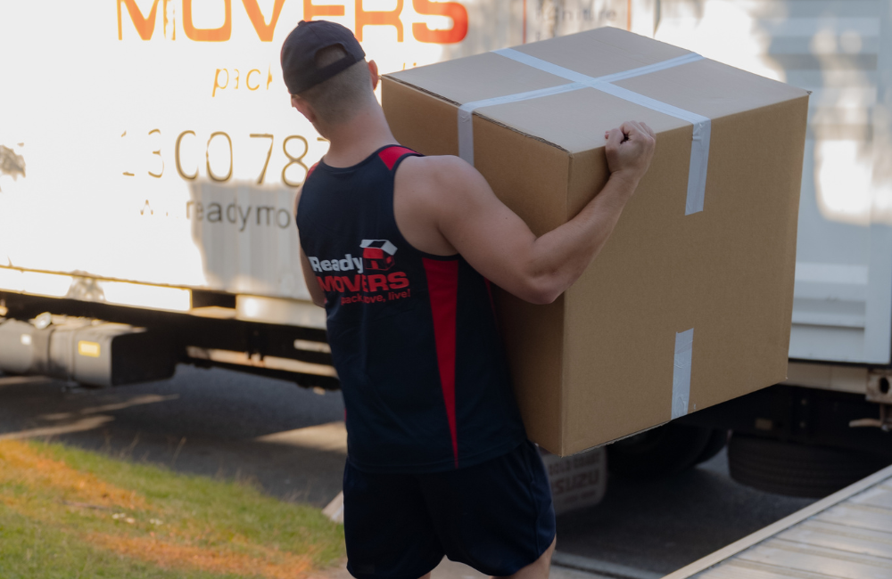 A Ready Movers removalist carrying a ox out towards the moving truck. 