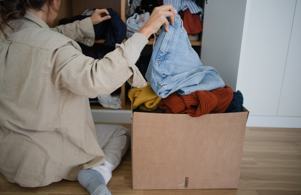 A women sorting through clothes and placing them into a box.