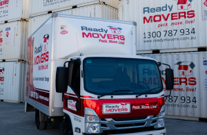 A Ready Movers removalist truck parked in front of Ready Movers shipping containers.