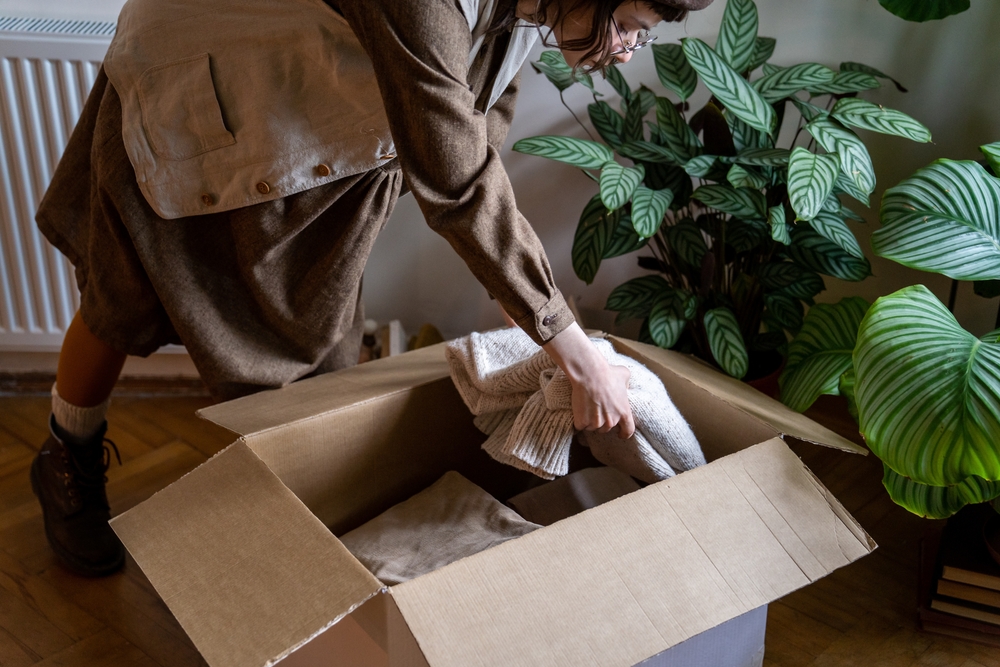 A woman packing jumpers into a box. 