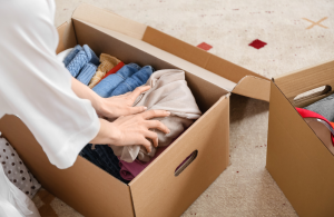 A woman's hands folding and packing clothes into a box.